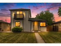 Charming two-story home features a front yard, balcony, and freshly painted white brick exterior at 3550 Eudora St, Denver, CO 80207