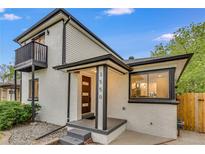 A modern home has a painted brick exterior with black trim and a balcony overlooking the front yard at 3550 Eudora St, Denver, CO 80207