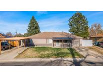 Charming single-story home with a covered front porch, attached garage and carport on a sunny day at 724 Ursula St, Aurora, CO 80011
