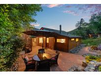 Cozy back patio area with stone pavers, seating, and large umbrella at 2874 Se Grapevine Rd, Idledale, CO 80453
