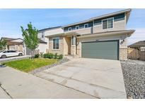 Two-story home with a driveway, green lawn, stone veneer, and two-car garage at 4644 Hatcher Dr, Brighton, CO 80601