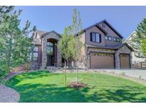 Two-story home featuring a well-manicured lawn, stone accents, and a three-car garage at 6078 Bridle Path Ln, Parker, CO 80134