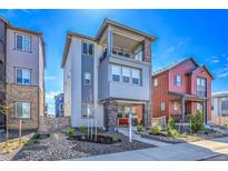 Inviting two-story home featuring a covered porch and second-story balcony with stone and blue-grey siding accents at 8728 Hotchkiss St, Littleton, CO 80125