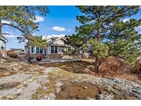 View of the rear of the home with stone accents, windows, and a concrete patio at 7515 Pineridge Trl, Castle Pines, CO 80108