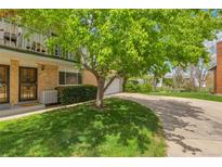 Charming townhome featuring a brick facade, well-maintained lawn, and mature trees at 387 Upham St, Lakewood, CO 80226