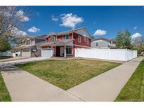 Charming two-story red home featuring a well-manicured lawn and bright white fence at 5552 Odessa St, Denver, CO 80249