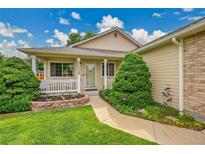 Inviting home exterior featuring a well-manicured lawn, charming front porch, and beautiful landscaping at 13112 Summit Grove Pkwy, Thornton, CO 80241