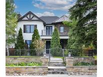Beautiful two-story home with a stone and wrought iron fence and manicured landscaping at 2646 S Madison St, Denver, CO 80210
