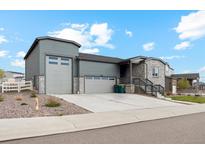 Charming home with a gray exterior, well-manicured lawn, a stone facade, and a spacious driveway at 5385 Trails Edge Ln, Castle Rock, CO 80104