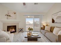 This light filled living room has a cozy fireplace, sliding doors to the balcony, and neutral decor at 8200 E 8Th Ave # 8202, Denver, CO 80230