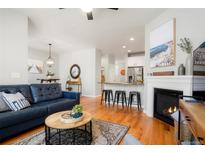 Cozy open-concept living room featuring a modern fireplace, hardwood floors, and a stylish blue leather couch at 8427 E 35Th Ave, Denver, CO 80238