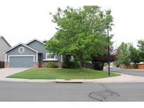 Charming one-story home featuring a well-manicured lawn and mature trees at 213 Mesa St, Brighton, CO 80601