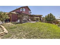 Landscaped backyard featuring a wooden pergola and patio, ideal for outdoor relaxation and entertaining at 10811 Chambers Way, Commerce City, CO 80022