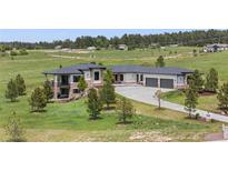 View of home featuring gray roof, outdoor patio, stone facade, manicured lawns, and garage at 2937 Hidden Den Ct, Franktown, CO 80116