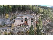 Secluded mountain home with stone accents and wooden deck nestled amongst trees at 900 Sawmill Creek Rd, Evergreen, CO 80439