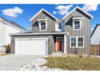 Two-story farmhouse-style home with gray siding, red door, and a white garage at 9324 Quartz St, Arvada, CO 80007