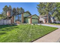 Charming green home featuring brick accents, large windows, manicured lawn and mature trees at 8820 W 80Th Dr, Arvada, CO 80005