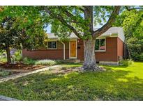 Charming brick home with mature trees and a well-manicured lawn, creating a welcoming curb appeal at 1395 S Kendall St, Lakewood, CO 80232