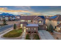 Beautiful two-story home featuring stone accents, a well-manicured lawn, and mountain views in the background at 19495 W 94Th Ave, Arvada, CO 80007