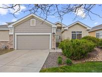Charming home featuring a two-car garage, stone accents, mature trees, and well-maintained lawn at 22312 E Plymouth Cir, Aurora, CO 80016