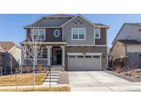 Two story home featuring a covered porch, stone accents, and a two-car garage at 8240 S White Crow St, Aurora, CO 80016