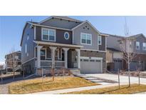 Charming two-story home featuring a covered porch, stone accents, and a two-car garage at 8240 S White Crow St, Aurora, CO 80016