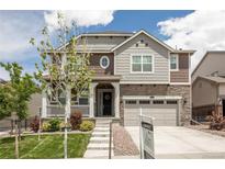 Charming two-story home featuring stone accents, a welcoming porch, and a well-manicured lawn at 8240 S White Crow St, Aurora, CO 80016