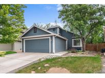 Charming blue two-story home featuring a two-car garage and lush front yard at 13341 Birch Cir, Thornton, CO 80241