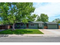 Charming home with green exterior, mature trees, and a well-manicured lawn creates a welcoming curb appeal at 5986 Dunraven St, Golden, CO 80403