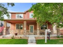 Charming two-story home featuring a welcoming front porch with stone accents and a well-maintained lawn at 11034 Nome St, Commerce City, CO 80640
