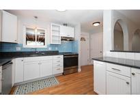 Bright kitchen with white cabinets, stainless steel appliances, blue backsplash, granite counters and hardwood floors at 945 Waite Dr, Boulder, CO 80303
