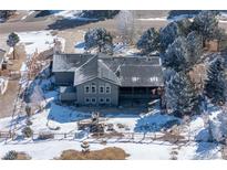 Charming home boasts a spacious backyard with a deck and firepit, surrounded by snow-covered trees at 20290 Doewood Dr, Monument, CO 80132