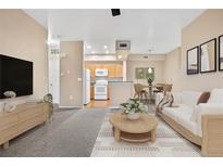 Open concept living room featuring a dining area and partial view of kitchen appliances and light-toned interior design at 8422 S Upham Way # G47, Littleton, CO 80128