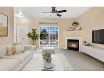 Bright living room with a fireplace, ceiling fan and sliding door to a balcony with seating at 8422 S Upham Way # G47, Littleton, CO 80128