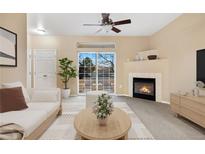 Bright living room with a fireplace, a ceiling fan, and a sliding glass door leading to an outdoor balcony at 8422 S Upham Way # G47, Littleton, CO 80128