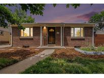 Charming brick home featuring a well-maintained front yard and a welcoming entryway with a beautiful dusk sky at 457 S Locust St, Denver, CO 80224