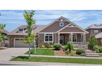 Charming single Gathering home featuring stone and siding exterior, manicured lawn, and a welcoming front porch at 27485 E Nova Pl, Aurora, CO 80016