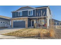 Charming two-story home featuring a stone facade, blue siding and a well-manicured lawn at 614 Moose St, Frederick, CO 80530