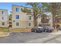 Tan apartment building with large shade trees and marked parking spaces at 9700 E Iliff Ave # C20, Denver, CO 80231