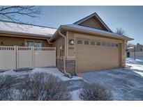 Tan home with a two car garage and stone accents on a sunny winter day at 8588 W Quarles Pl, Littleton, CO 80128