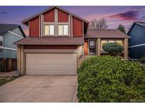 Two-story home featuring red wood siding and a brick-accented garage with manicured landscaping at 13339 E Idaho Pl, Aurora, CO 80012