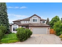 Two-story home with brick accents, a well-manicured lawn, and a two-car garage on a sunny day at 6643 Orion Ct, Arvada, CO 80007