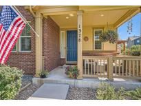 Inviting covered front porch featuring brick accents and a hanging flower basket, enhancing curb appeal at 1378 S Duquesne Ct, Aurora, CO 80018