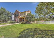 Charming two-story home with brick and siding exterior, well-manicured lawn, and white picket fence on a sunny day at 1378 S Duquesne Ct, Aurora, CO 80018