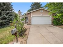 Charming home featuring a two-car garage, stone accents and mature trees in a lush green lawn at 2750 S Rifle St, Aurora, CO 80013