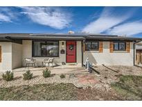 Charming home featuring a bright red door, solar panels, shuttered windows, and quaint front yard landscaping at 327 S Xanadu St, Aurora, CO 80012