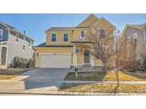 Charming yellow two-story home with well-maintained front yard, and a two car garage at 10622 Racine St, Commerce City, CO 80022