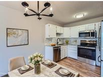 Bright kitchen features white cabinetry, stainless steel appliances, and marble countertops, complemented by a modern chandelier at 3184 S Heather Gardens Way # 302, Aurora, CO 80014