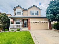 Charming two-story home featuring a front porch, manicured lawn, and an attached two-car garage at 21238 Snowshoe Ln, Parker, CO 80138