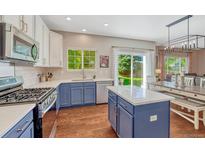 Bright kitchen featuring stainless steel appliances, island, quartz countertops, and backyard access at 21238 Snowshoe Ln, Parker, CO 80138